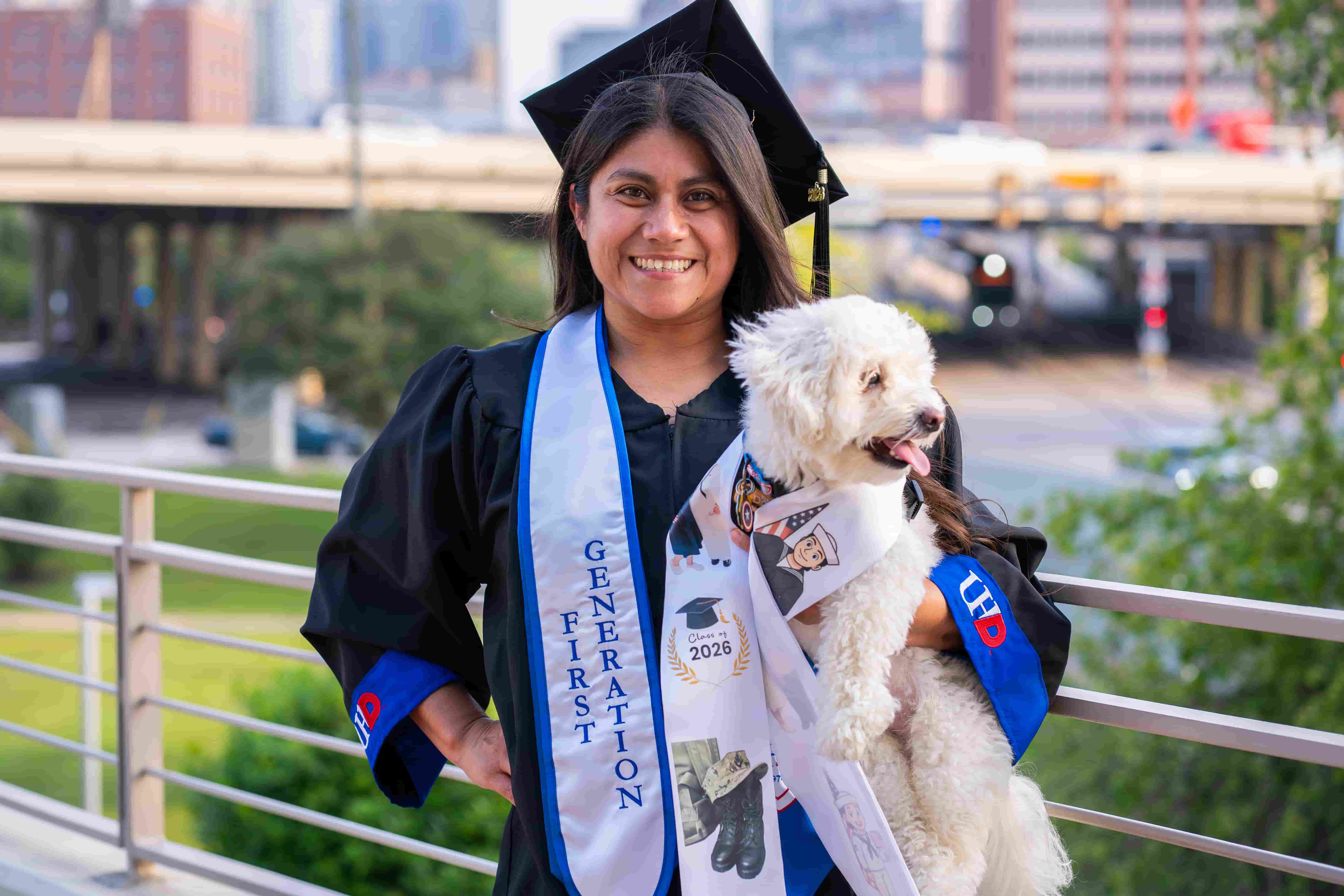 student in her UHD grad cap and gown with city scape 