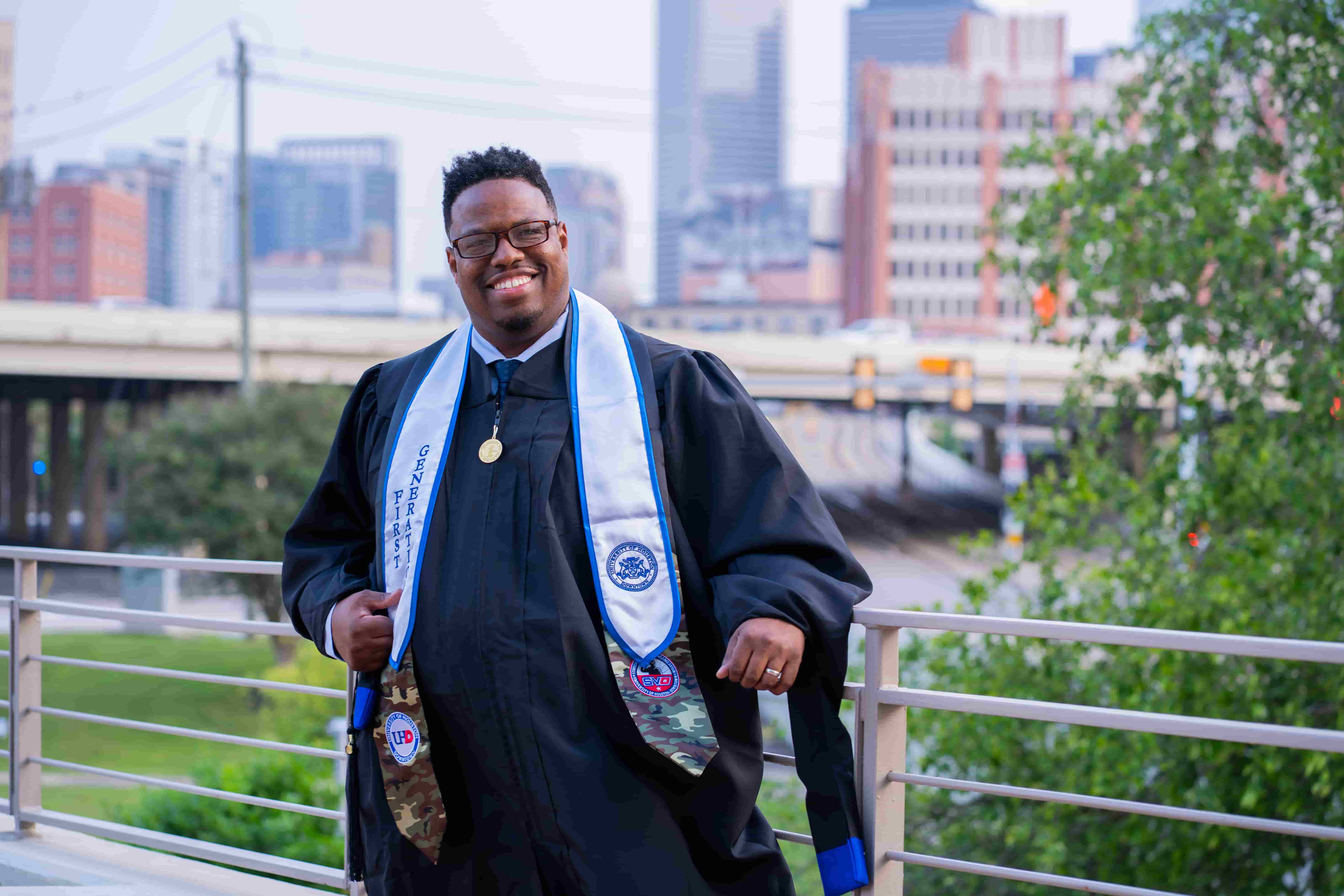 male graduate with a veterans stole with city scape in background