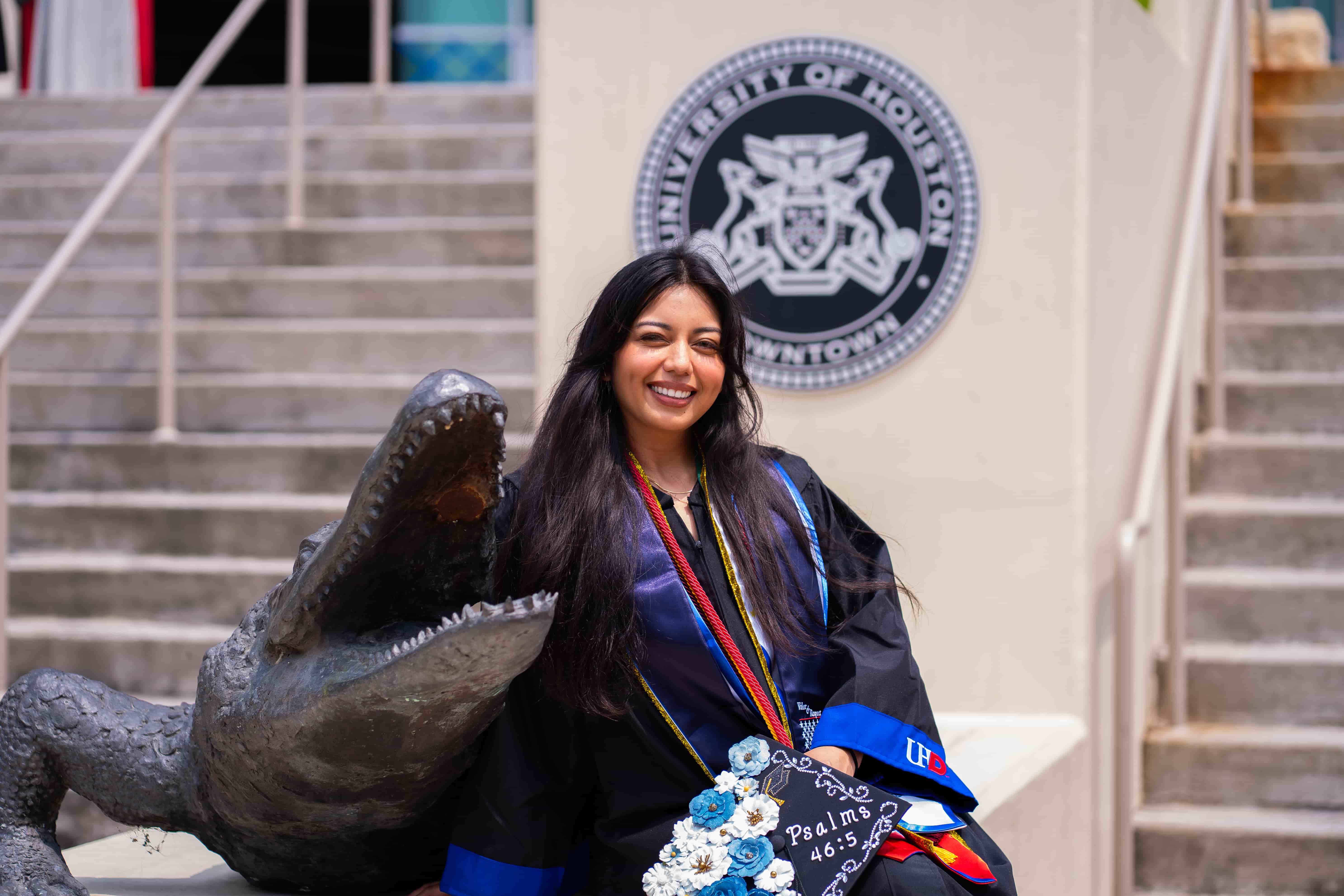 female graduate sitting with the UHD gator statue