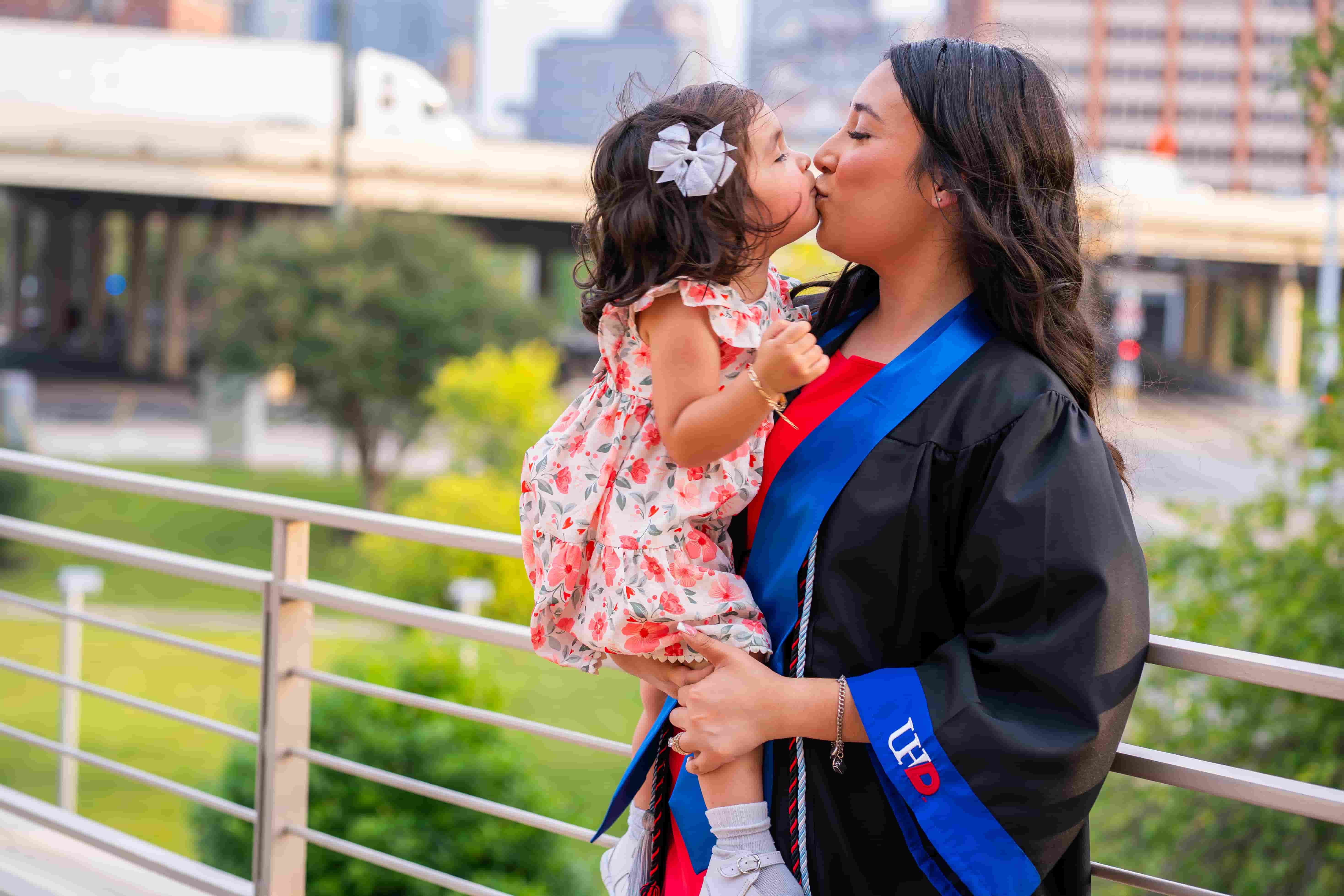 a female graduate kissing her daughter with her grad gown on