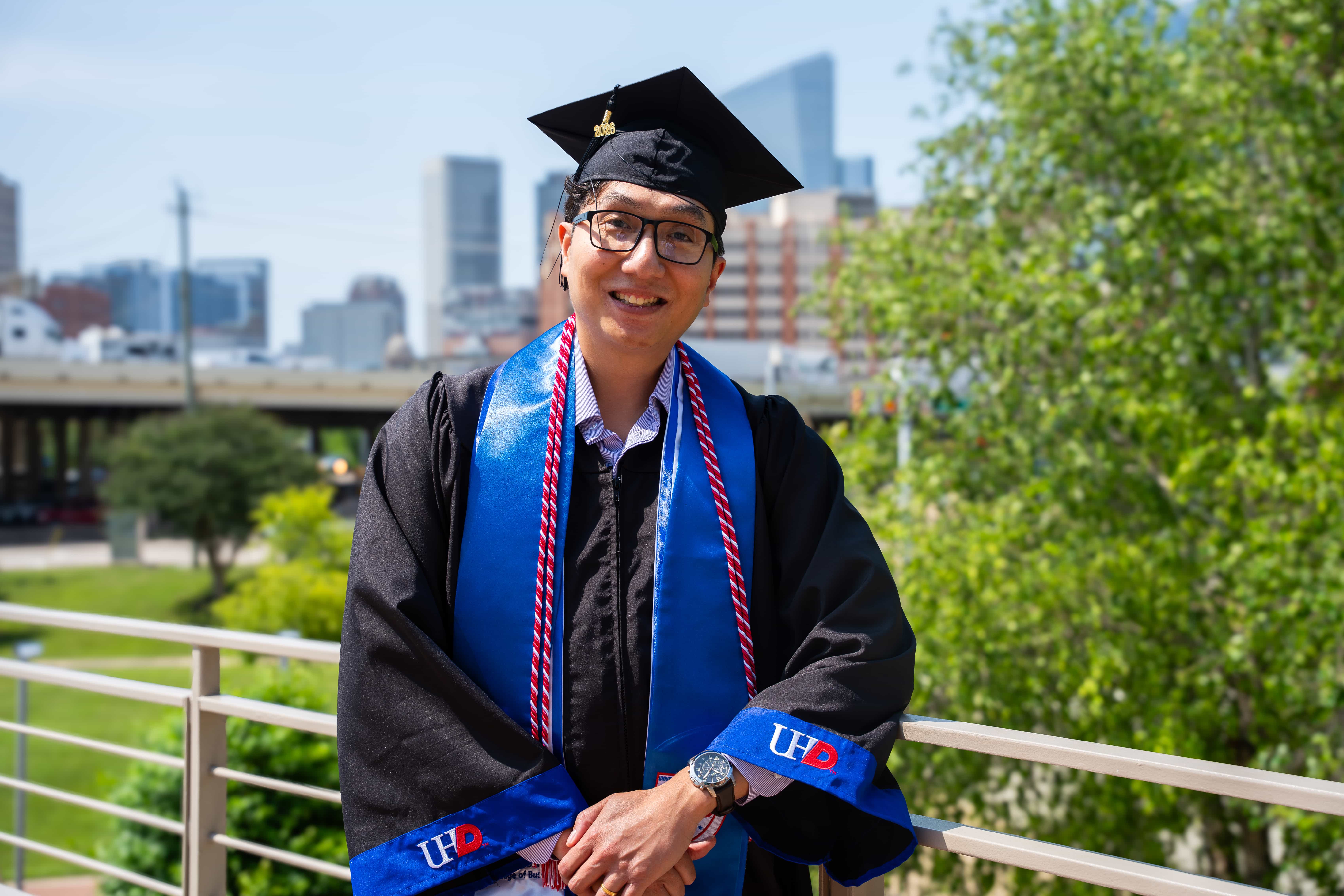 male graduate student posing with the city scape background