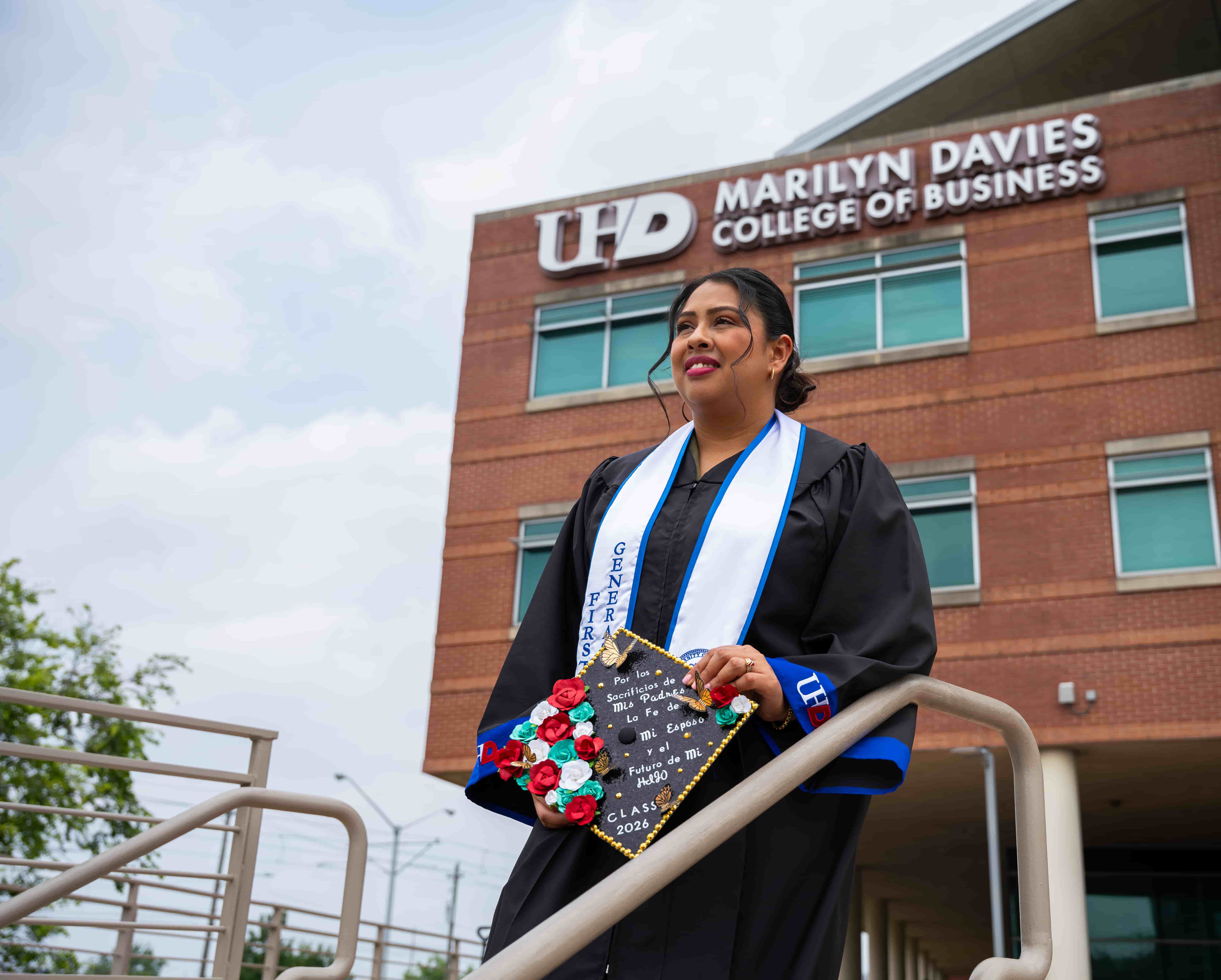 a female graduate with the marilyn davies college of business behind her