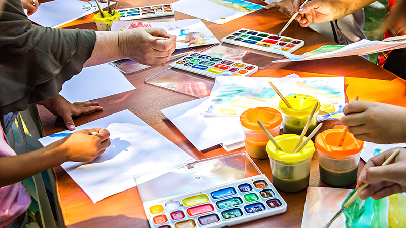 Water color paints and paper spread across a table