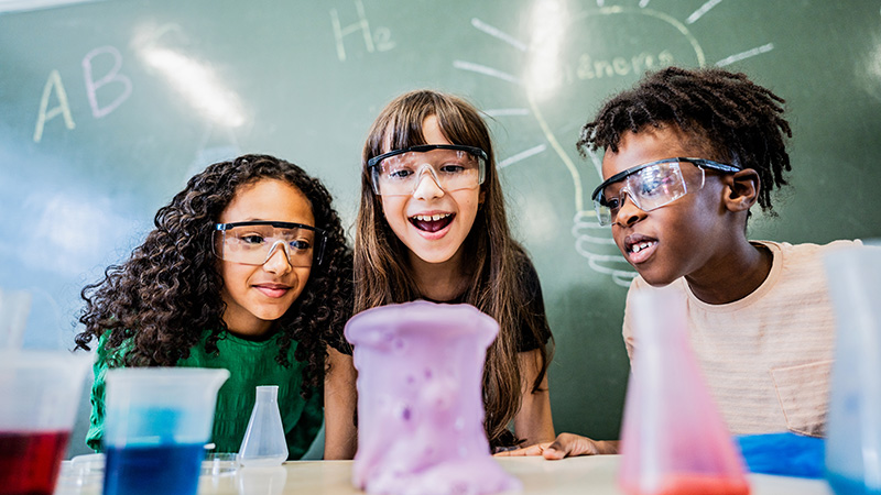 Three teenagers watching ooze in a beaker