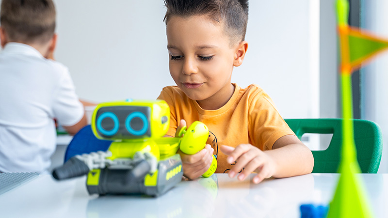 Young boy playing with a green toy robot