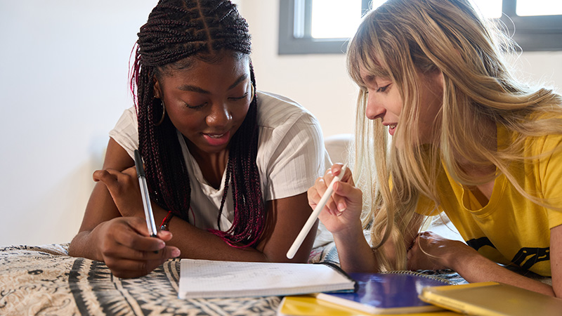 Two teenage girls writing and talking
