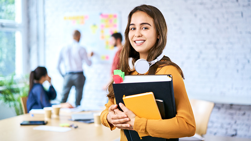 Teenage girl holding books in a classroom
