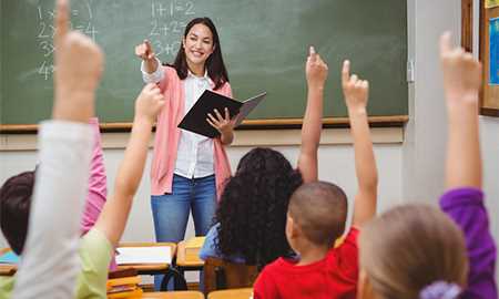 Teacher in classroom with hands raised