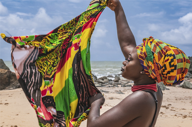 woman dancing on the beach of Axim, Ghana in colorful headdress and scarf