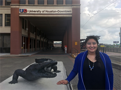 Photo of UHD History major Helen Martinez next to alligator statue in front of UHD main building