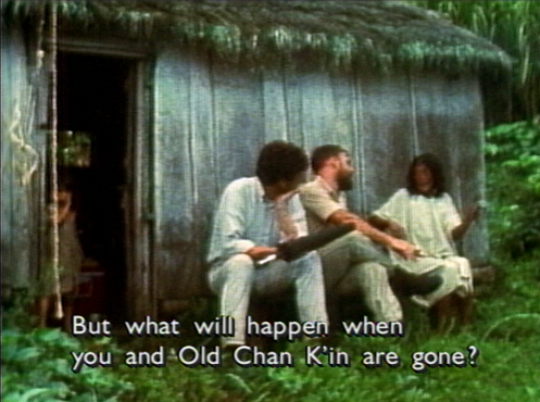 three people talking outside of a hut