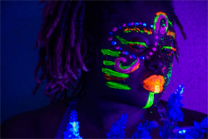 person with face painted shown in black light
