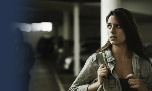 Woman walking in a dark parking lot being followed