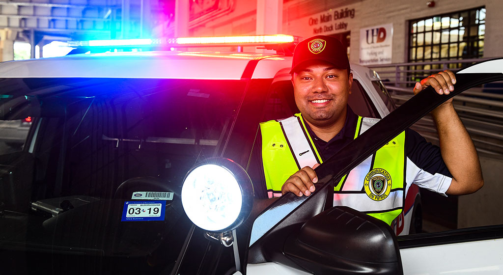 Public officer, next to a police vehicle.