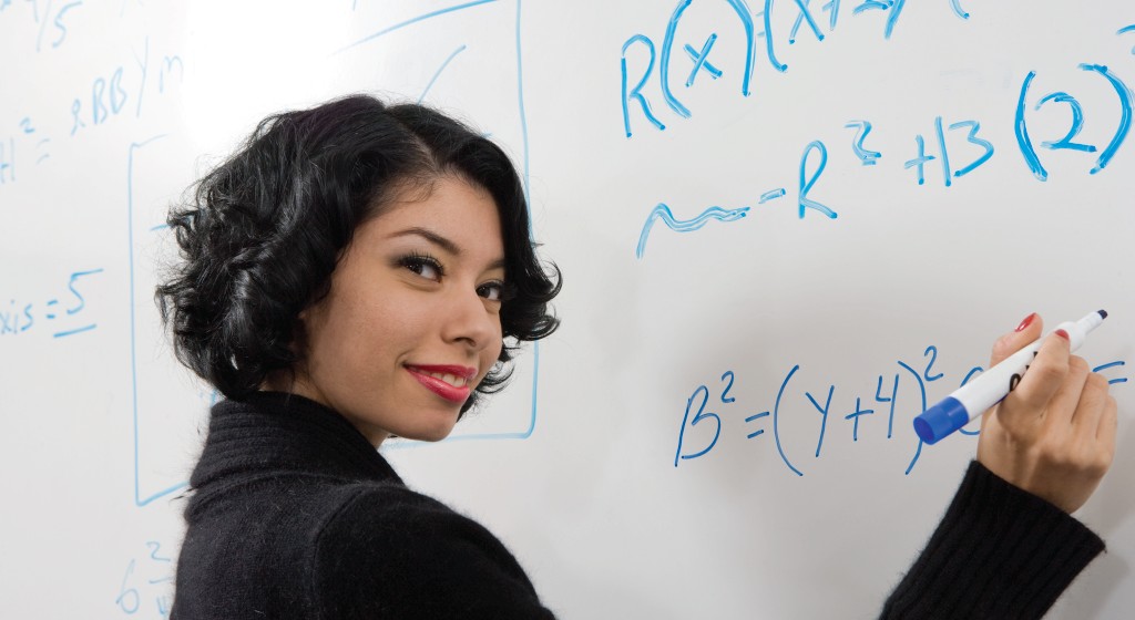 Woman writing an equation on a whiteboard.