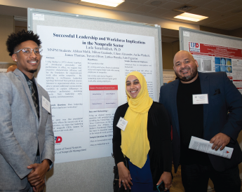 Three students standing in front of research