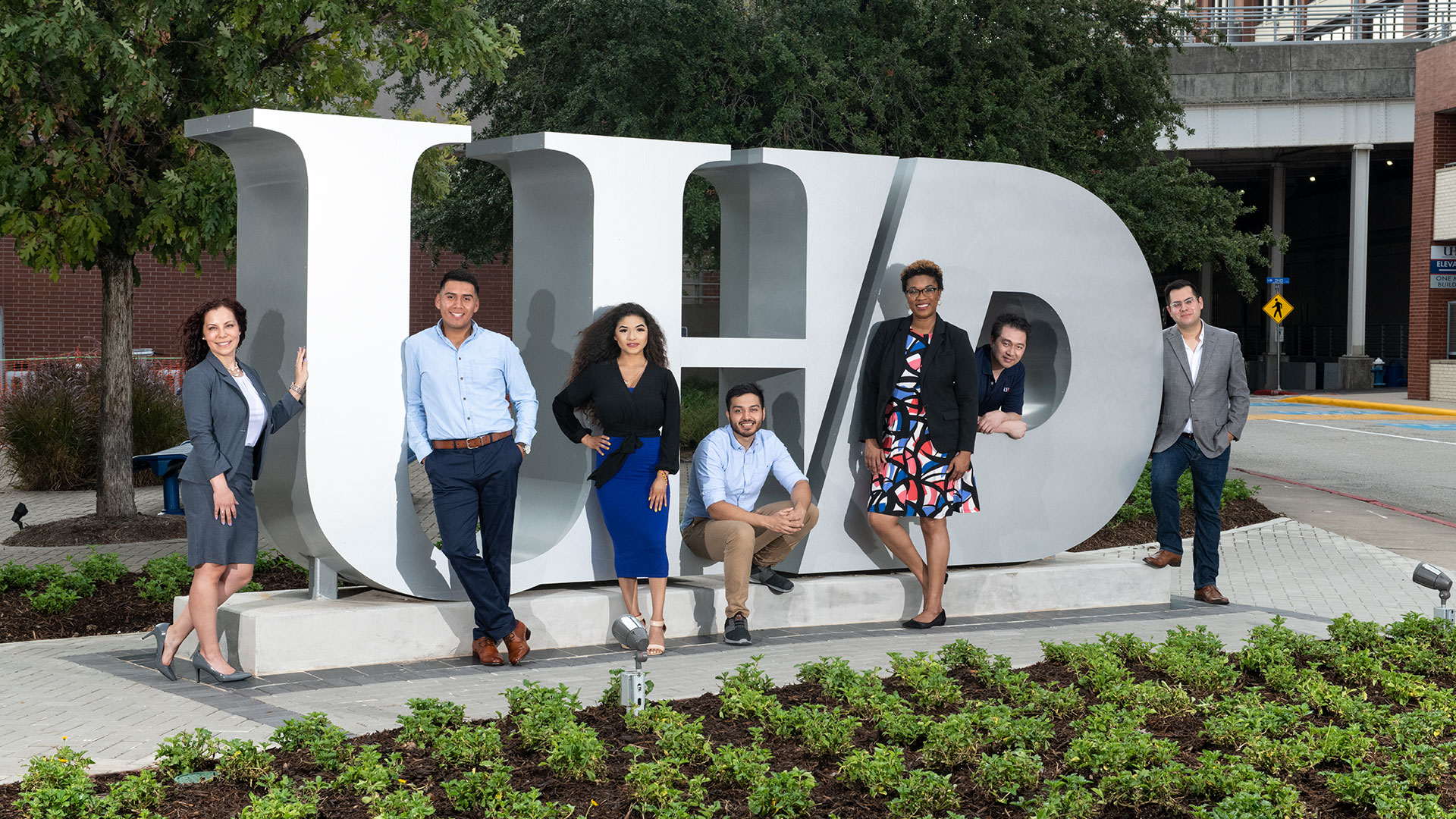 group of UHD students standing around the UHD Silver lettering on campus