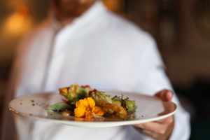 chef holding out a gourmet dish
