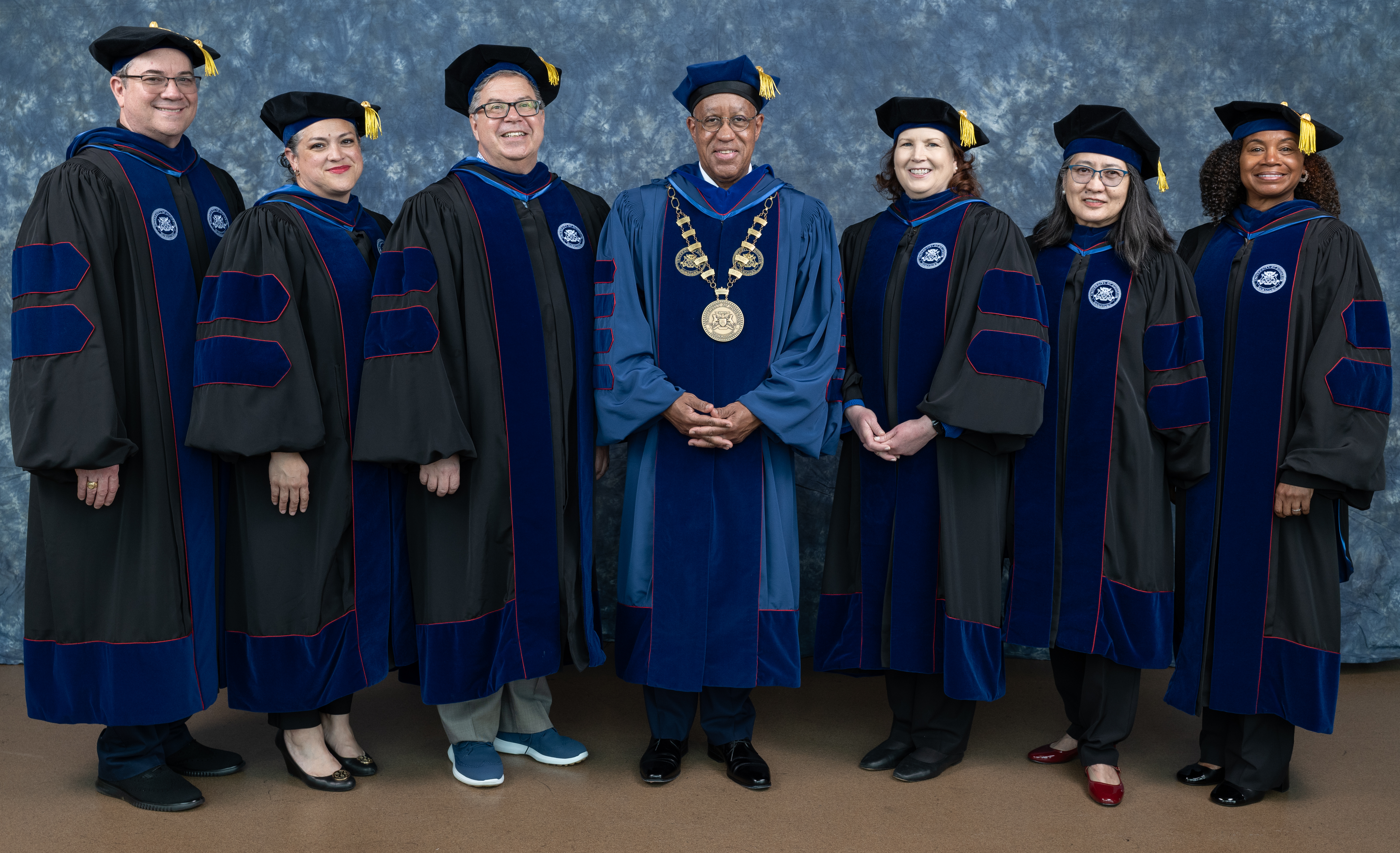 7 vip members with black robes in front of a backdrop