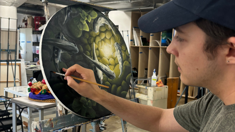 UHD art student paints on a round canvas during class