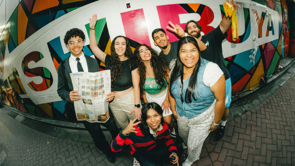 UHD students post in front of a painted sign