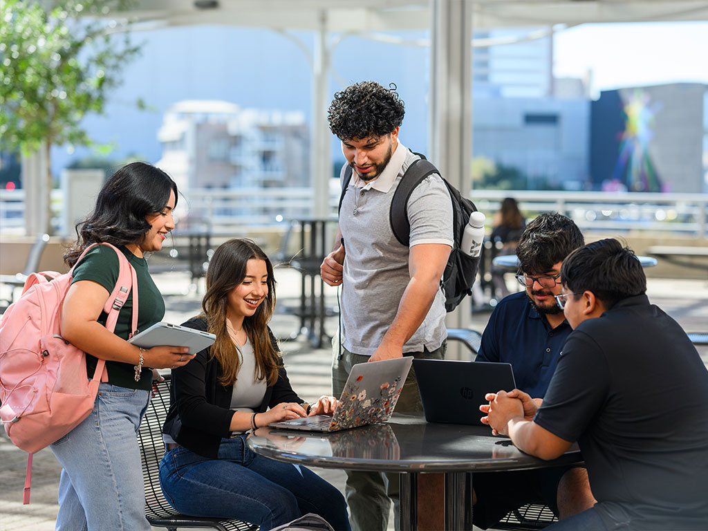 Students talking around a laptop