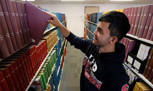 student selecting a book from the stacks