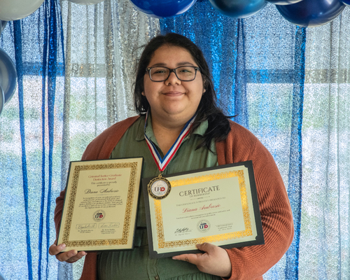 diana ambrosio holds two award certificates at an awards ceremony at the university of houston downtown