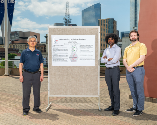 Hong Lin stands aside a research presentation poster with  Kibru Menore and Sam Holden on University of Houston-Downtown's south deck