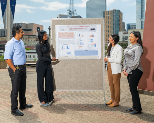  Mesias Pedroza, Ph.D.; Nethra Kippip, Patricia Amador, and Yuliana Sants stand aside a research poster on the covid-19 pandemic