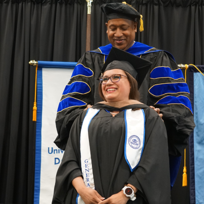 Student receives graduate hood during ceremony.