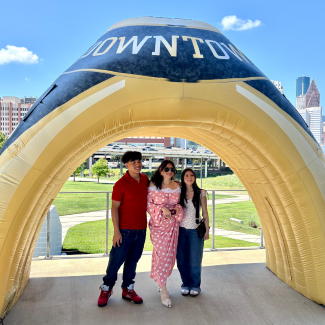 Students showing off their class rings beneath an inflatable UHD ring.