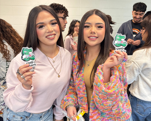 Two early college high school south students from pasadena isd hold up stickers with the university of houston-downtown's mascot edugator at Bayou Bound