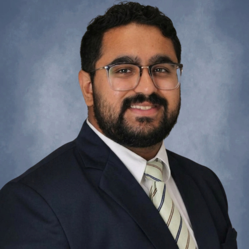 Graduate Admissions Counselor Jesvin Kuruvila smiles in a suit and tie at the university of houston-downtown