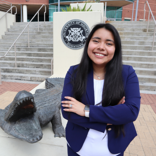 Marketing sophomore Kemberley Osorto stands aside an alligator statue at the marilyn davies college of business at the university of houston-downtown