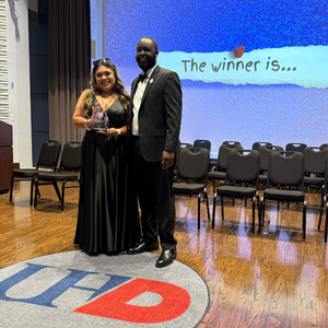 A student award winner smiles while holding an award next to Tremaine Kwasikpui Director of the University of Houston-Downtown's Student Leadership & Involvement