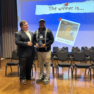 A student smiles while holding an award for the university of houston-downtown's esports 