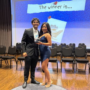 A university of houston-downtown student wearing a cocktail dress stands next to a student in a suit at the university's awards ceremony called one main event