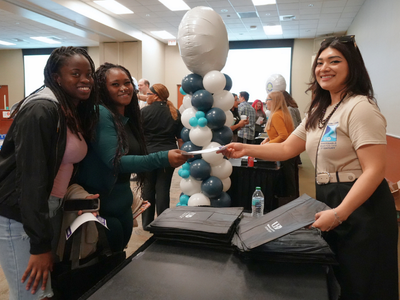 Yesnia Sanchez hands a bag to university of houston-downtowns students at a pep rally for the university's quality enhancement plan