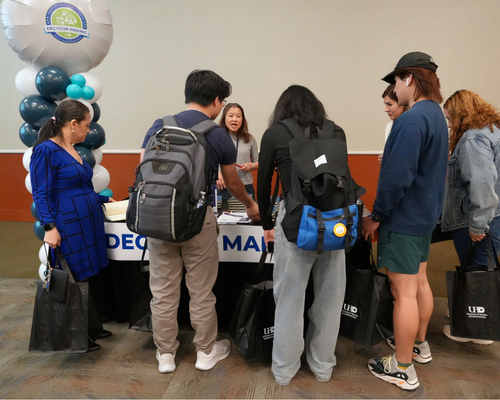 Students gather around a microcredential table for communication at the qep pep rally at the university of houston-downtown