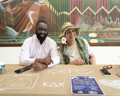Tremaine Kwasikpui Director, Student Leadership & Involvement sits aside Assistant Vice President, University Relations Debra McGaughey at a chalk drawing activity table at the quality enhancement plan pep rally at the university of houston-downtown