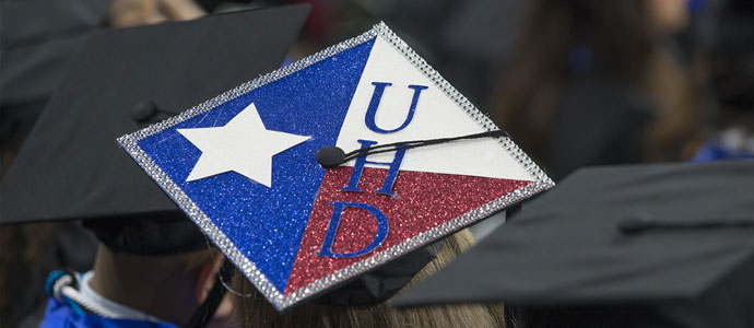 UHD decorated graduation cap among traditional black caps
