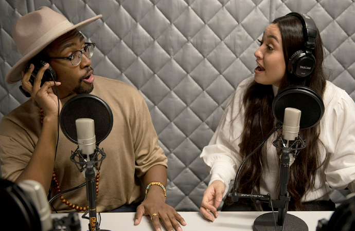 Students with headsets on speaking into microphones at a radio studio