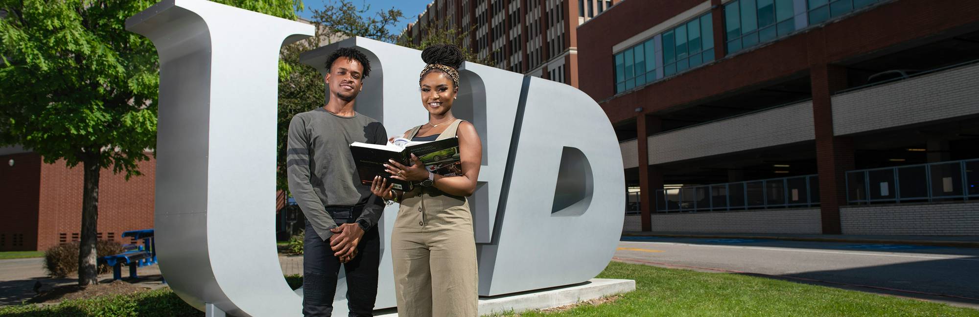 UHD student at the front of UHD logo statue