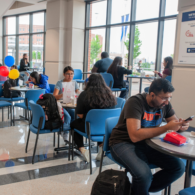 University of Houston-Downtown students sit at indoor tables while eating lunch