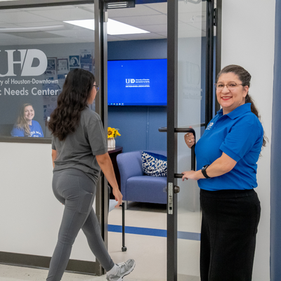 Hope Pacheco, Assistant Dean of Student Advocacy & Assistance, opens the door of the Basic Needs Center at UHD for a student while a staff member smiles in the office