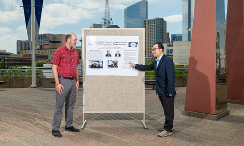 Dr. timothy Redl, University of Houston-Downtown professor of mathmatics and chair for department of mathmatics and statistics, stands aside a research poster. University alum and Redl's mentee Timothy Duong points to their presentation poster for their senior research project on AP statistics analysis for college admission