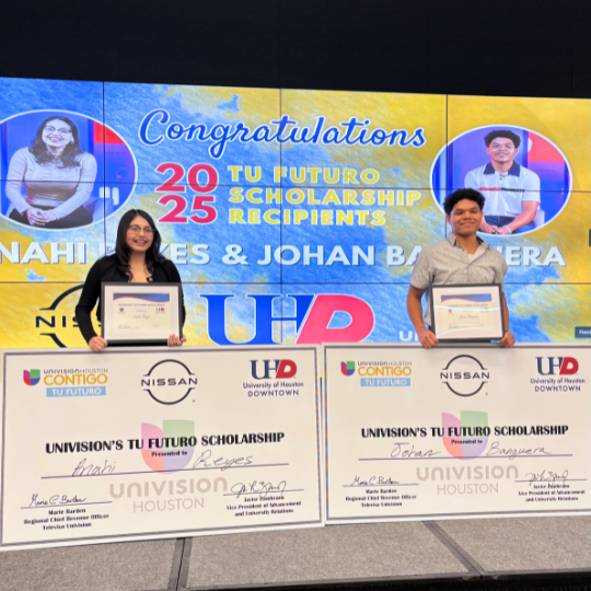 Two high school seniors smile while holding award certificates and giant checks for UHD and Univision Houston's Tu Futuro Scholarship. The students are recipients of the 2025 Tu Futuro Scholarship to the University of Houston-Downtown. 