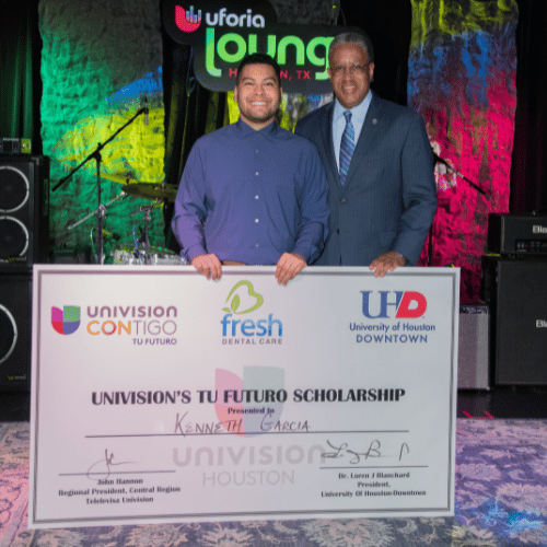 Kenneth Garcia stands with an oversized check with words that read Univision's Tu Futuro Scholarship Presidented to Kenneth Garcia. University of Houston Downtown President Loren Blanchard stands next to Garcia. 