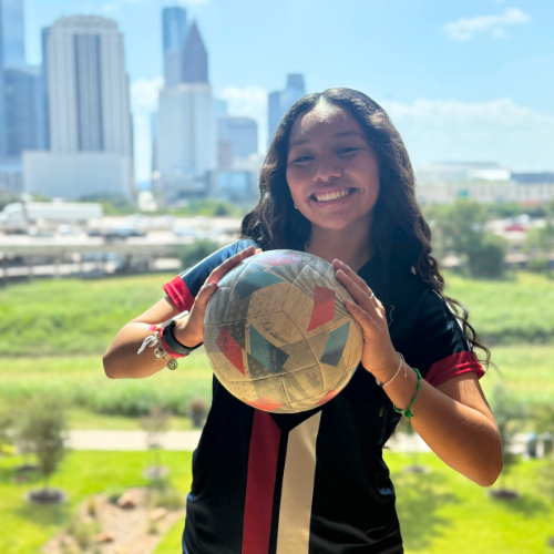 Member of the women's soccer team at the university of houston downtown holds a soccer ball 